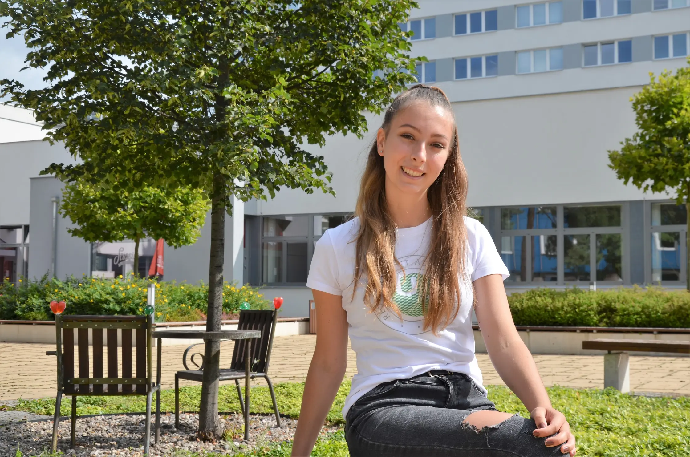 A young woman sitting on a bench in front of a building, enjoying a peaceful moment outdoors.